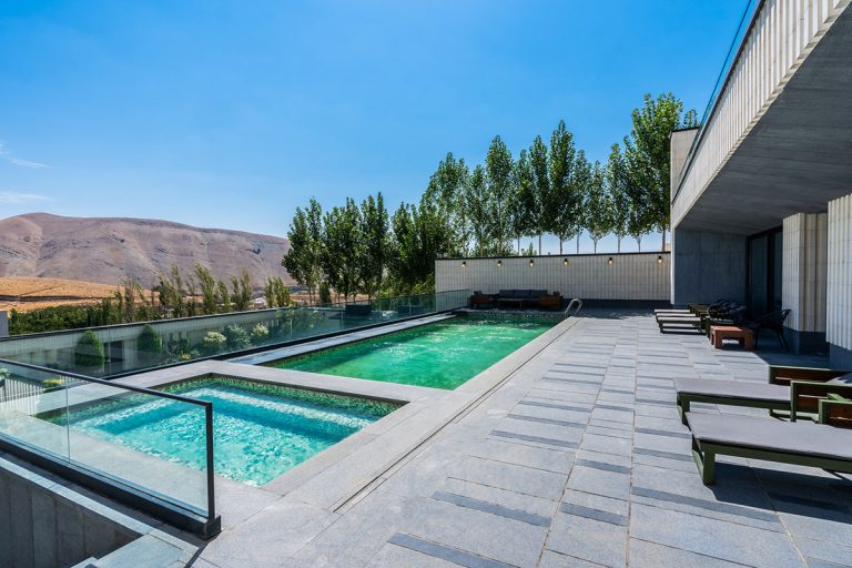 استخر و جکوزی با دیواره شیشه‌ای در فضای ویلای شهرک آنا