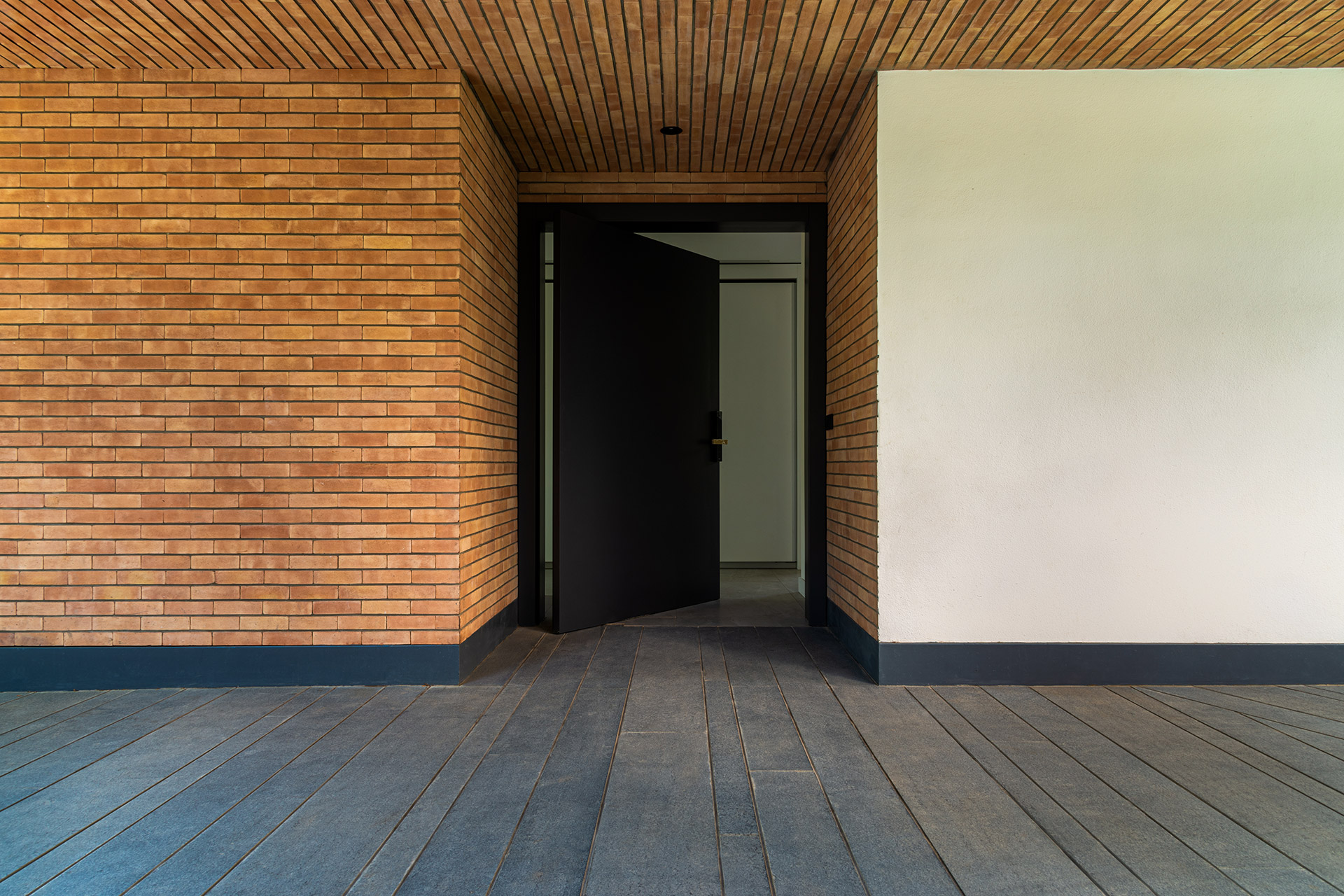 ورودی مینمال خانه کاتوزیان، نمای آجری در جوار گرانیت مشکی شرکت سنگ سروش