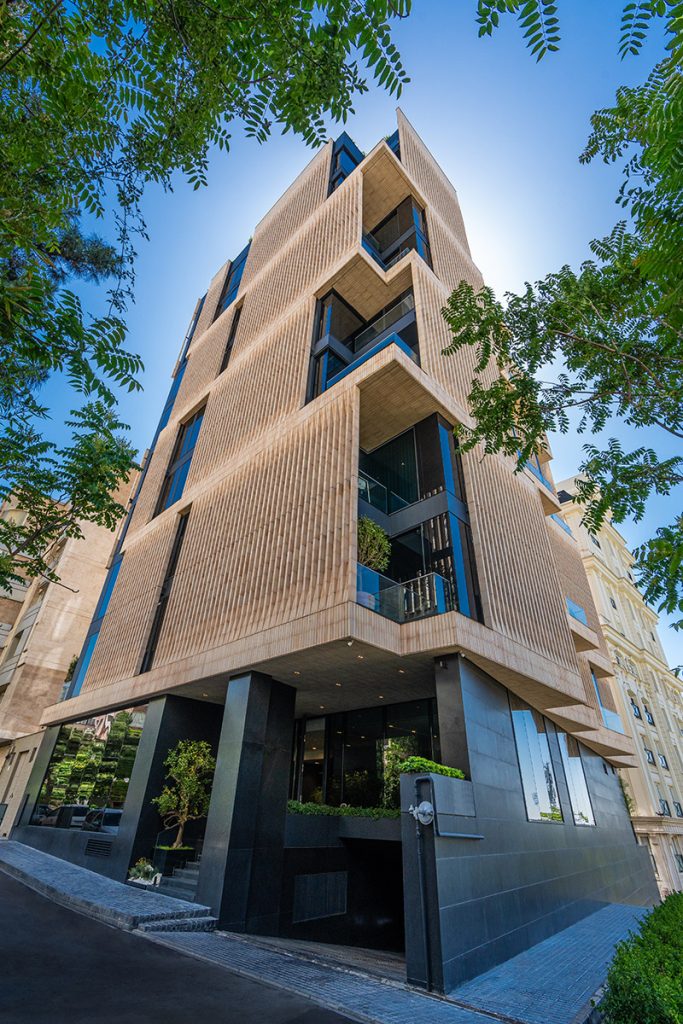 نمای کلی ساختمان لومن با زمینه آسمان آبی و پوشش گیاهی اطراف