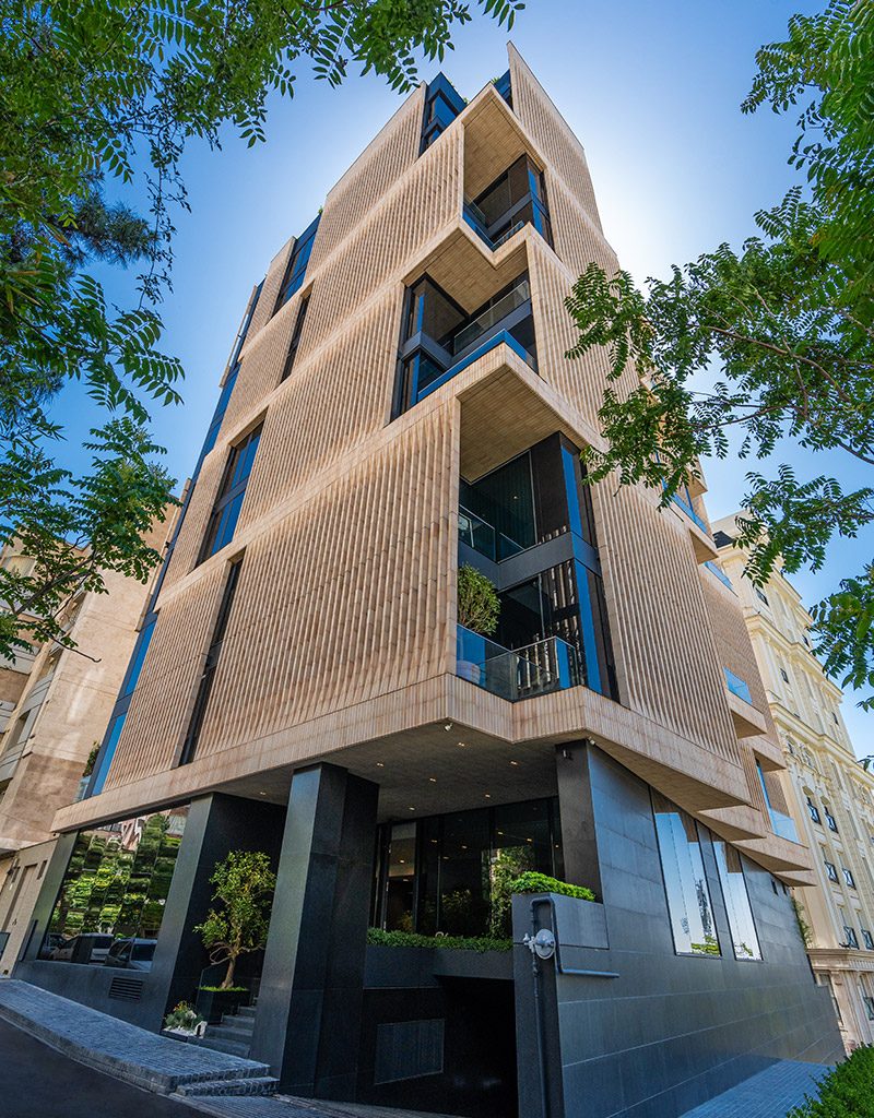 نمای کلی ساختمان لومن با زمینه آسمان آبی و پوشش گیاهی اطراف