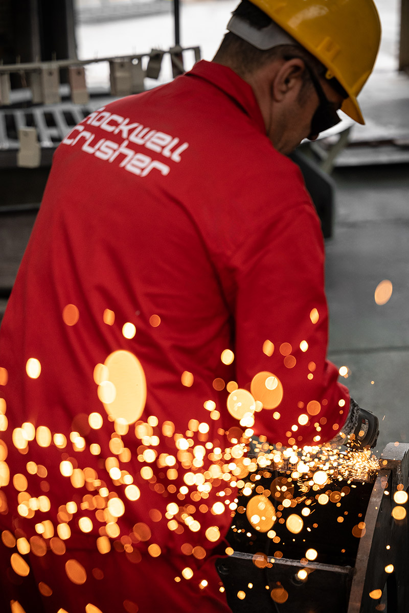 کارگر در حال کار با دستگاه فرز و پراکنش جرقه‌های نوری