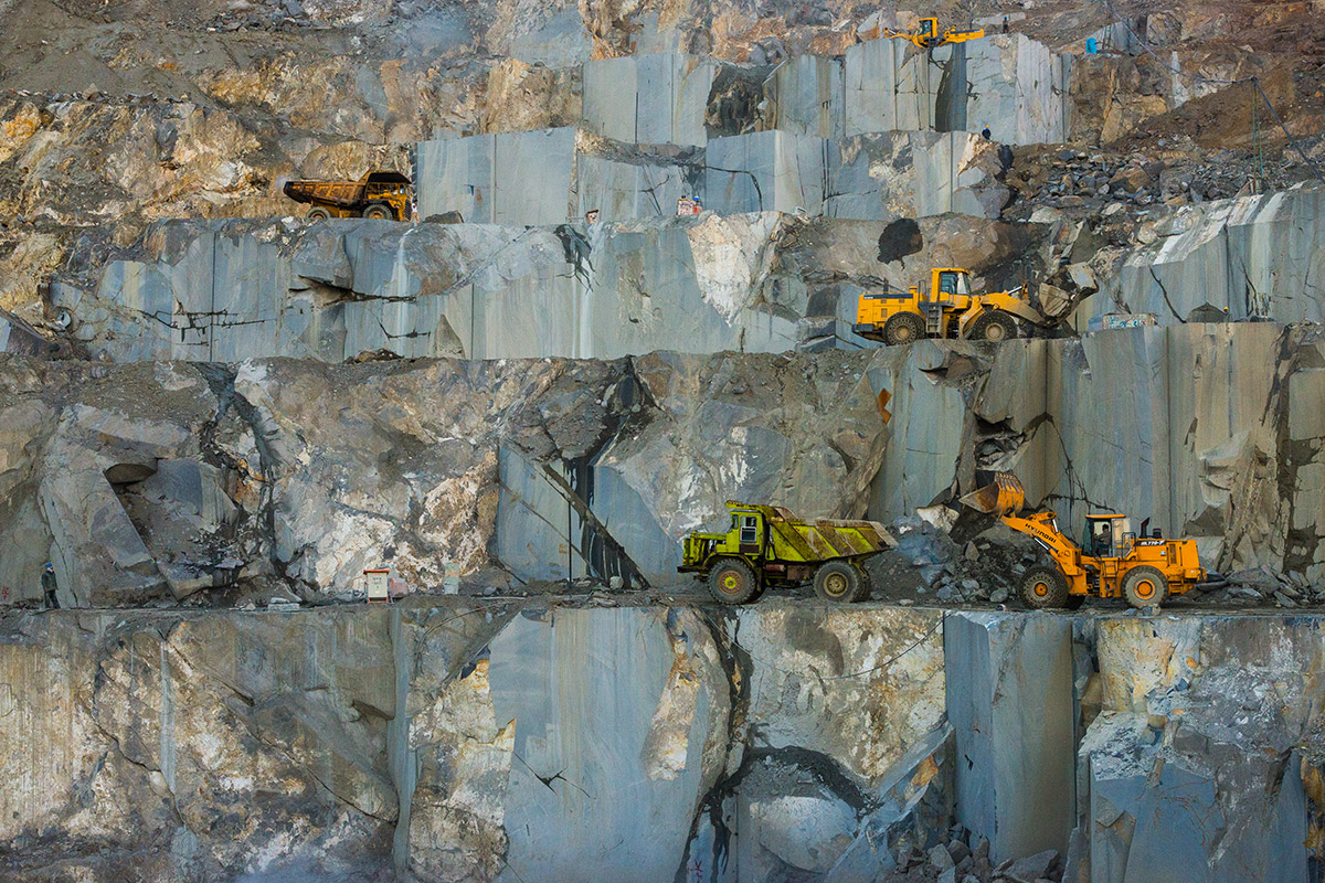 تصویری از ماشین‌آلات صنعتی فعال در سطوح پله‌ای معدن سنگ شفق