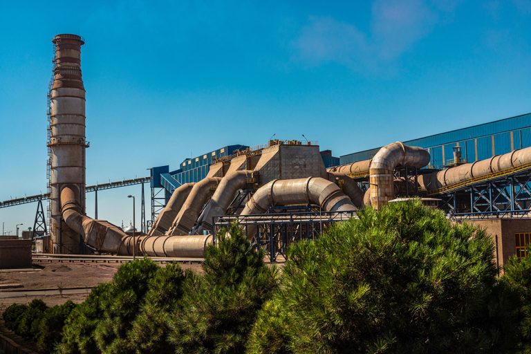 نمای روز کارخانه اپال پارسیان با لوله‌های عظیم و طبیعت اطراف