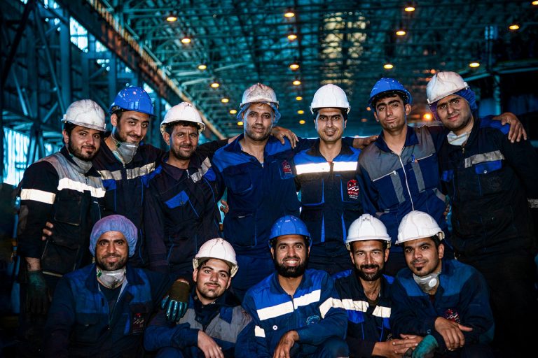 گروهی از کارگران با لباس‌های صنعتی در فضای کارگاهی