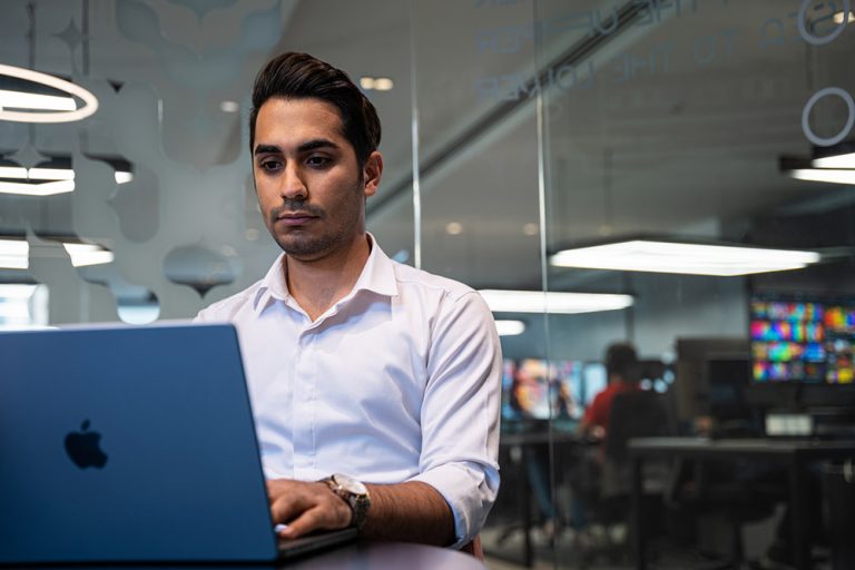 پرسنل مرد در حال کار با لپ‌تاپ در فضای شیشه‌ای شرکت اسپارا