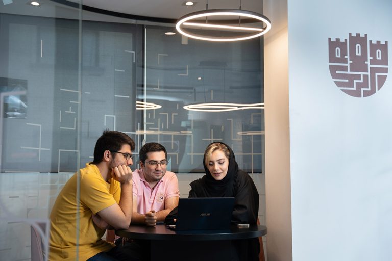 سه نفر از کارکنان شرکت اسپارا در حال گفت‌وگو و مرور اطلاعات روی لپ‌تاپ